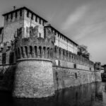 Explore a majestic gothic castle surrounded by a reflective moat, showcasing its medieval architecture.